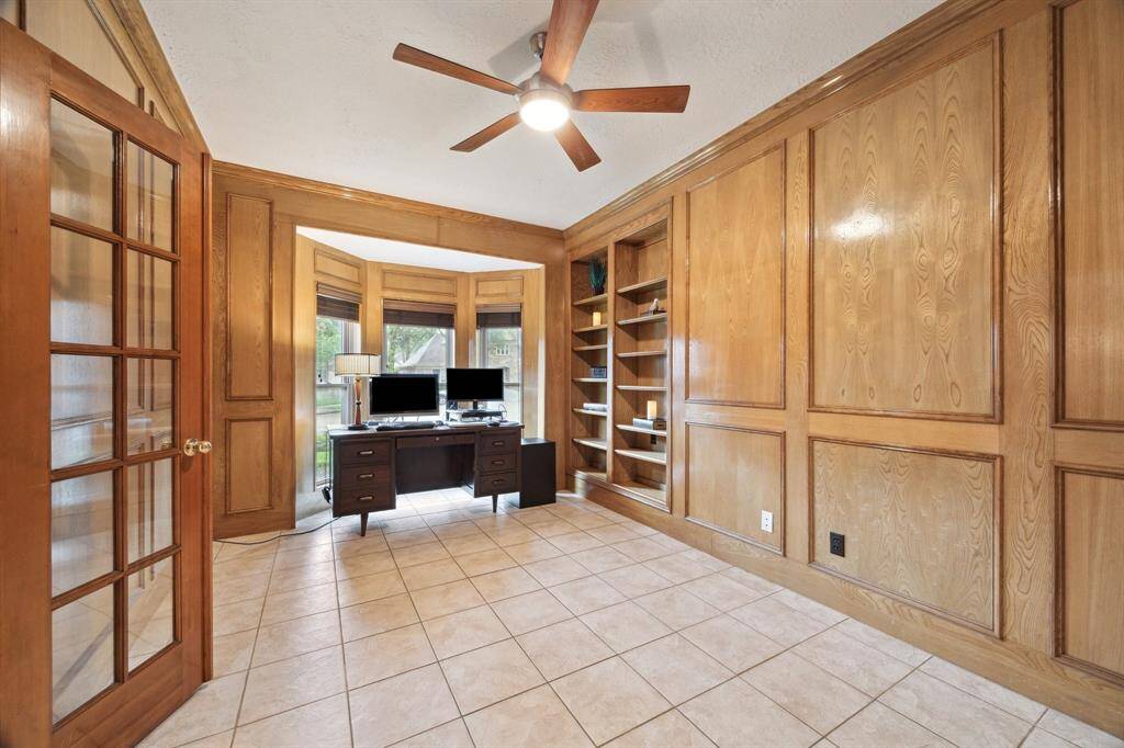 CUSTOM WOOD PANELING OFFERS DETAILED MOLDING AND BUILT-IN BOOK SHELVES.CERAMIC TILE AND CEILING FAN, AND A GREAT VIEW TO THE FRONT YARD ALLOWS NATURAL LIGHT IN.