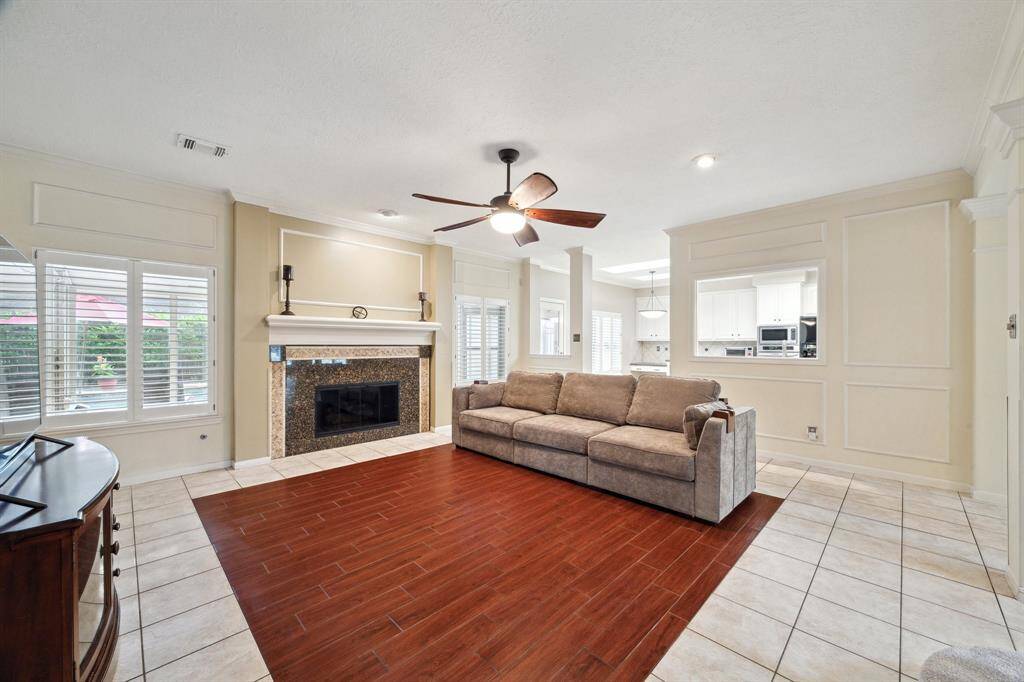 GAS LOG FIREPLACE HAS A GORGEOUS GRANITE BORDER AND DECORATIVE MOLDING. CERAMIC TILE WOOD LOOK DISTINGUISHES FAMILY ROOM AREA