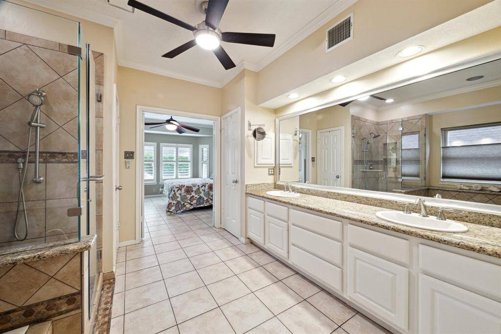 EN SUITE BATH FEATURES A SEAMLESS SHOWER, CEILING FAN AND CERAMIC TILE, AND PLENTY OF CABINET STORAGE BENEATH