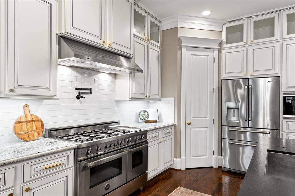 A chef’s dream kitchen featuring a Bertazzoni gas range, built-in griddle, pot-filler, and a spacious leathered granite island — perfect for cooking and entertaining.