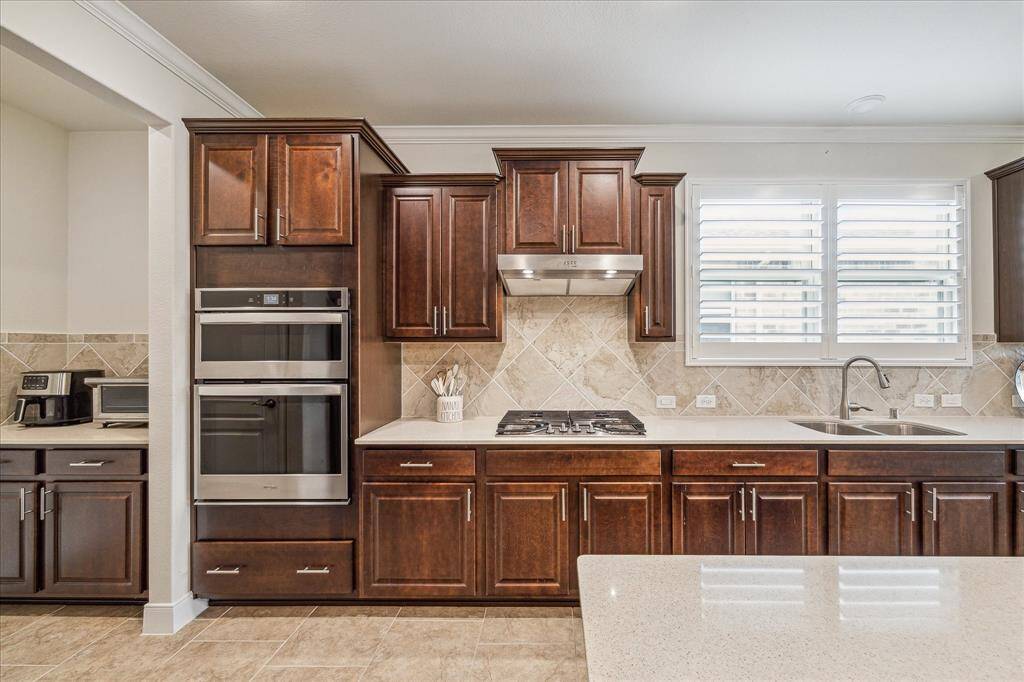 Microwave convection oven on top and full oven below, gas range, upgraded cabinetry. Butlers pantry left of ovens.