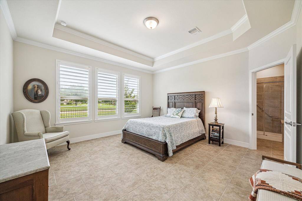 Spacious primary bedroom with abundant natural light, elegant tray ceiling, and serene views, offering a relaxing retreat.