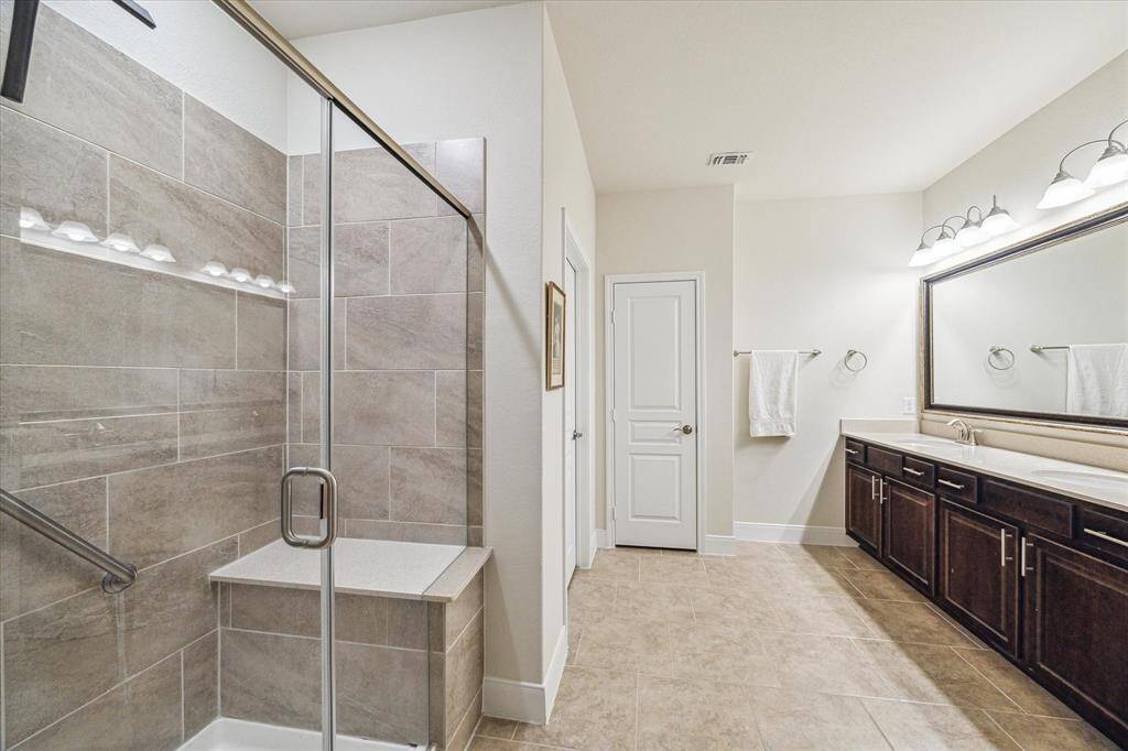 Luxurious primary bath featuring a spacious glass-enclosed shower, elegant dual-sink vanity, and modern fixtures for a spa-like retreat.