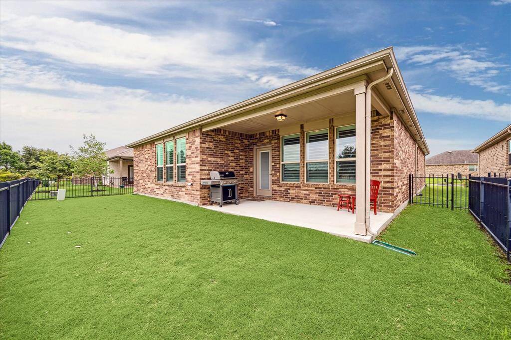 This photo showcases a spacious backyard with a covered patio, perfect for outdoor entertaining. The brick exterior adds charm, and the well-maintained lawn is enclosed by a fence, providing privacy and security.