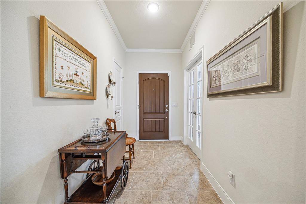Welcome to a home with an elegant entrance, featuring high ceilings and exquisite crown moldings throughout.
