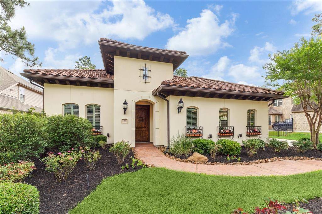 Mediterranean-style elevation features a tile roof, iron planter boxes, landscape lighting and stamped concrete for unmistakable curb appeal.
