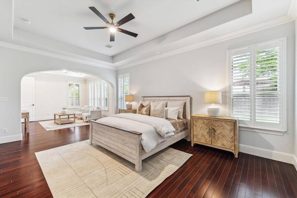 Stunning ensuite features tres ceilings, elegant crown molding, classic shutters, and rich wood flooring. A brand new ceiling fan complements the soothing color palette, creating a serene atmosphere.