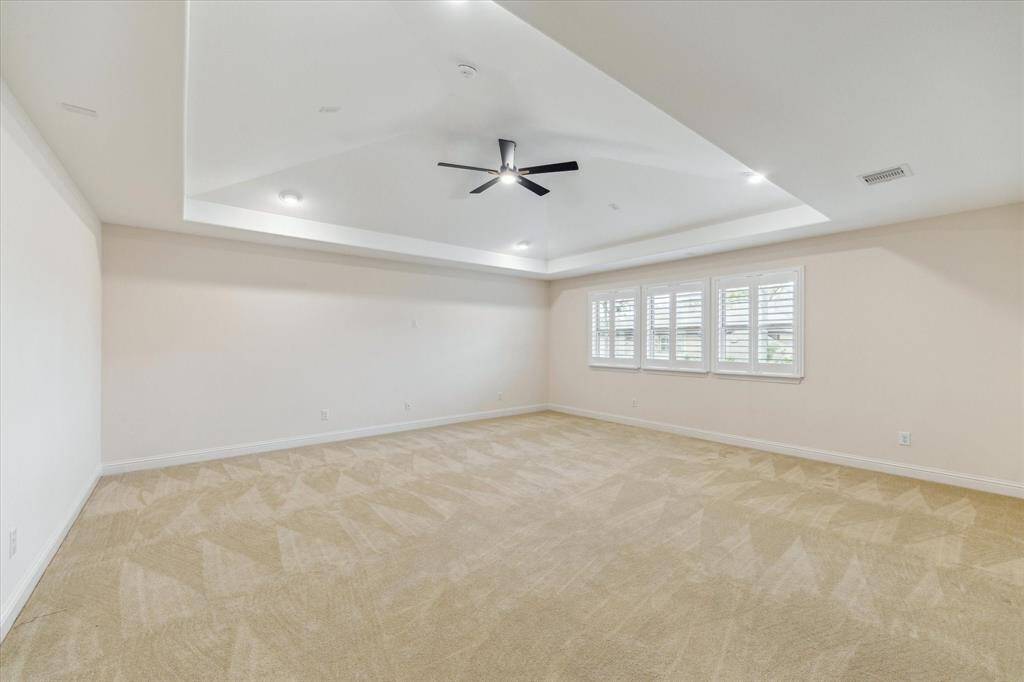 Enjoy endless possibilities in this large game room featuring a tres ceiling, new ceiling fan, plush carpeting, recessed lighting, and classic shutters.