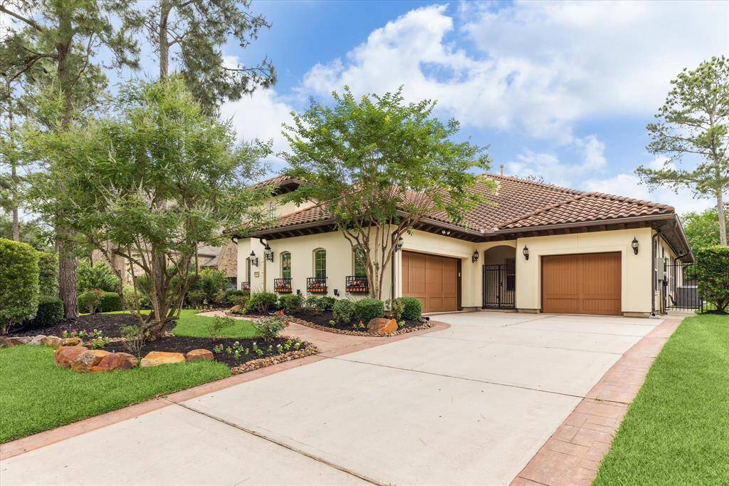 Three-car garage features impressive, real wood garage doors that add warmth and sophistication to the home's exterior. The driveway, lined with stylish stamped concrete, offers both functional parking and added curb appeal.