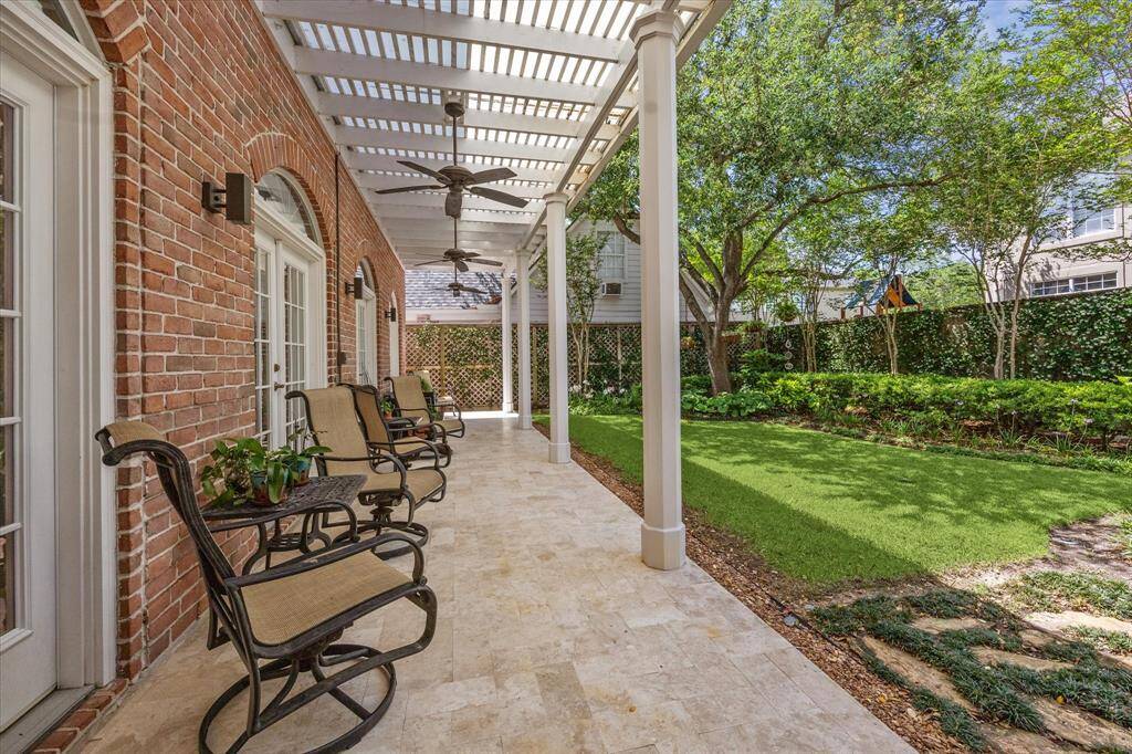 A relaxing full width patio paved with honed travertine that overlooks this beautiful landscaped backyard