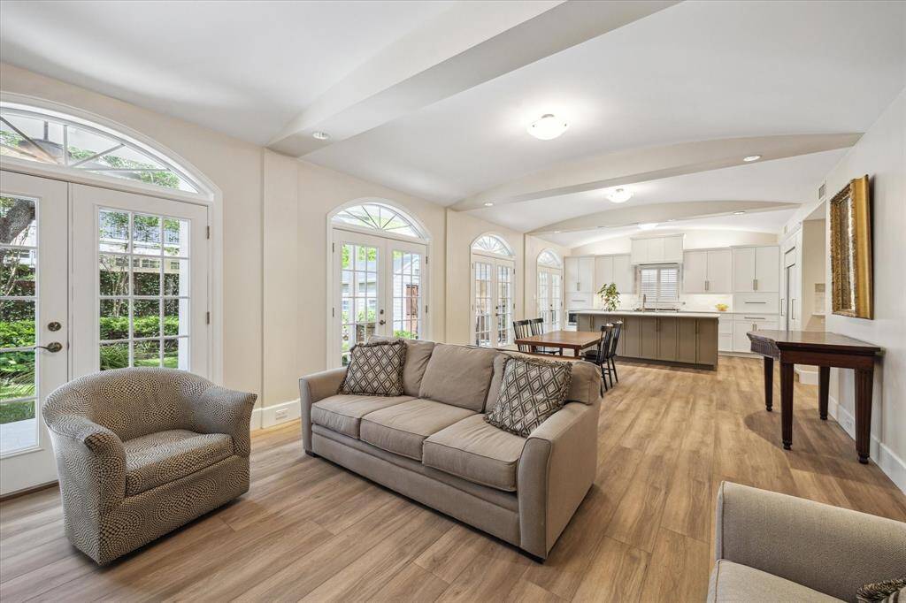 A view of the family/dining rooms and kitchen. There are 4 sets of French doors with arched fan-lite transom windows that open onto a honed travertine patio
