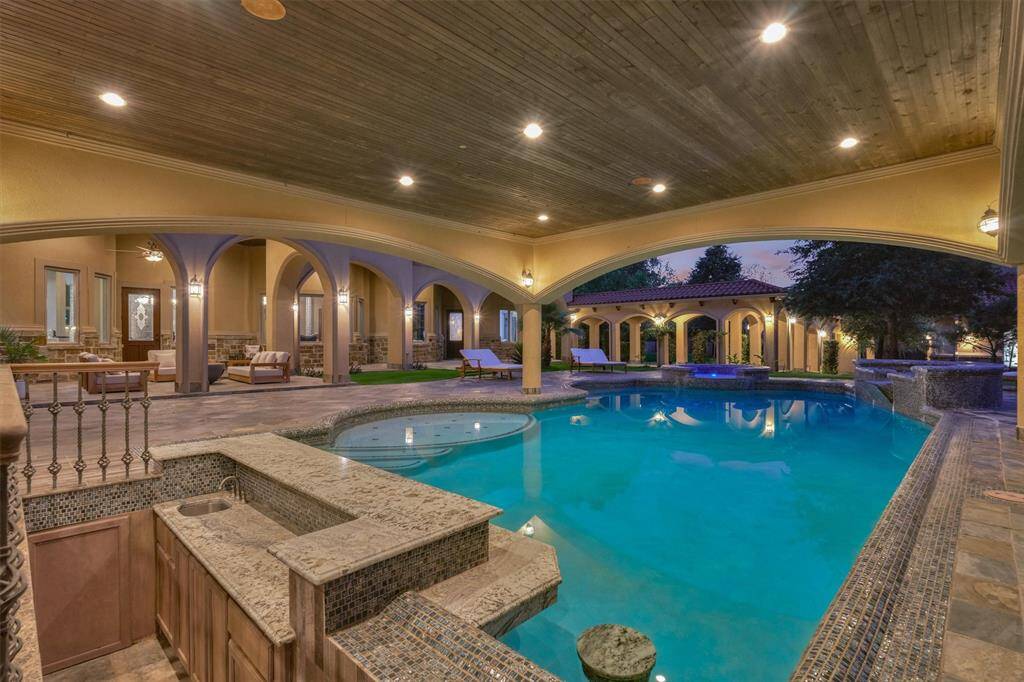 Resort-style pool with swim-up bar, sunken seating, and covered lounging space.