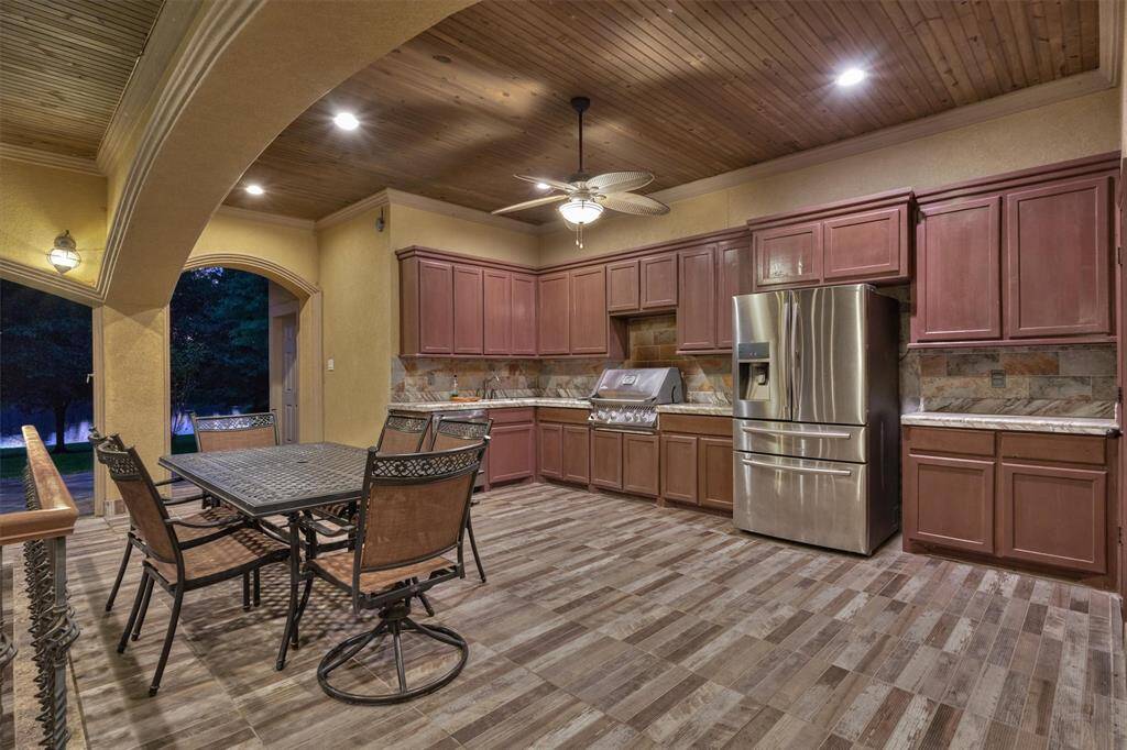 Complete outdoor kitchen with built-in grill, fridge, dishwasher, and sink—overlooking the pool and lake.