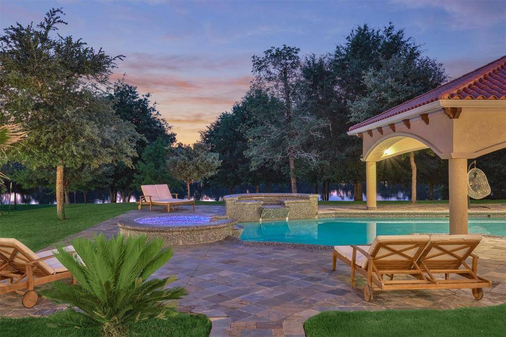 Tropical-inspired landscaping frames the pool area, offering privacy, shade, and vibrant greenery.