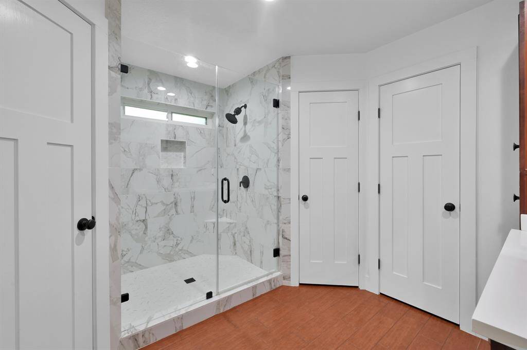 Newly renovated primary shower with sleek tilework and modern fixtures.