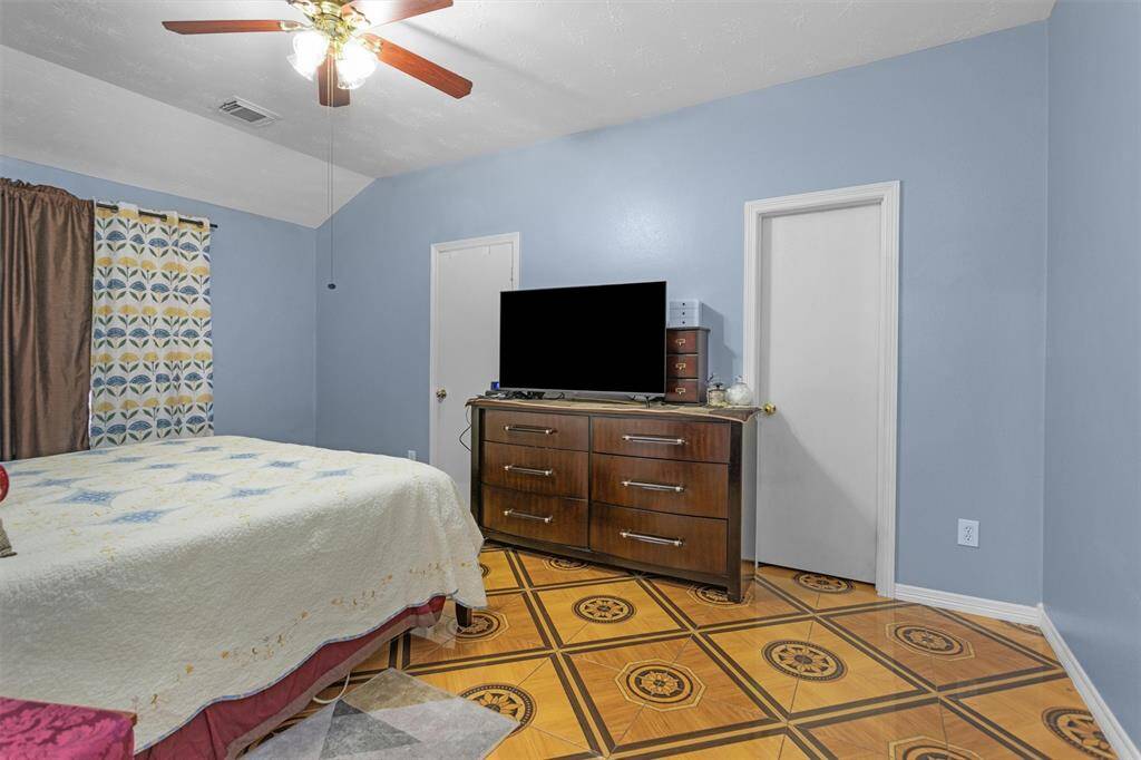 Spacious primary bedroom featuring soothing blue walls, stylish patterned flooring, and ample natural light, perfect for relaxation and comfort.