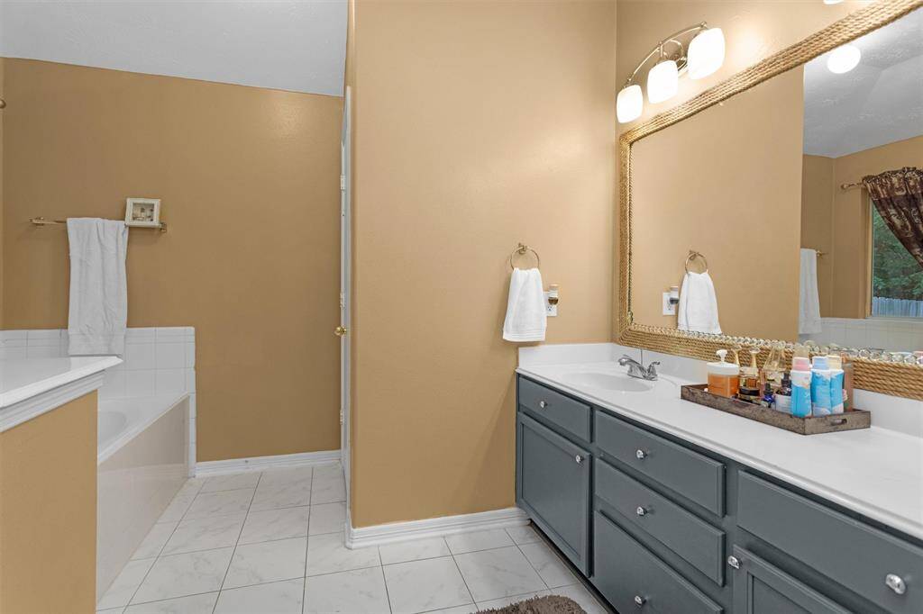 Elegant primary bathroom featuring a spacious vanity, modern lighting, and a relaxing tub—perfect for unwinding.
