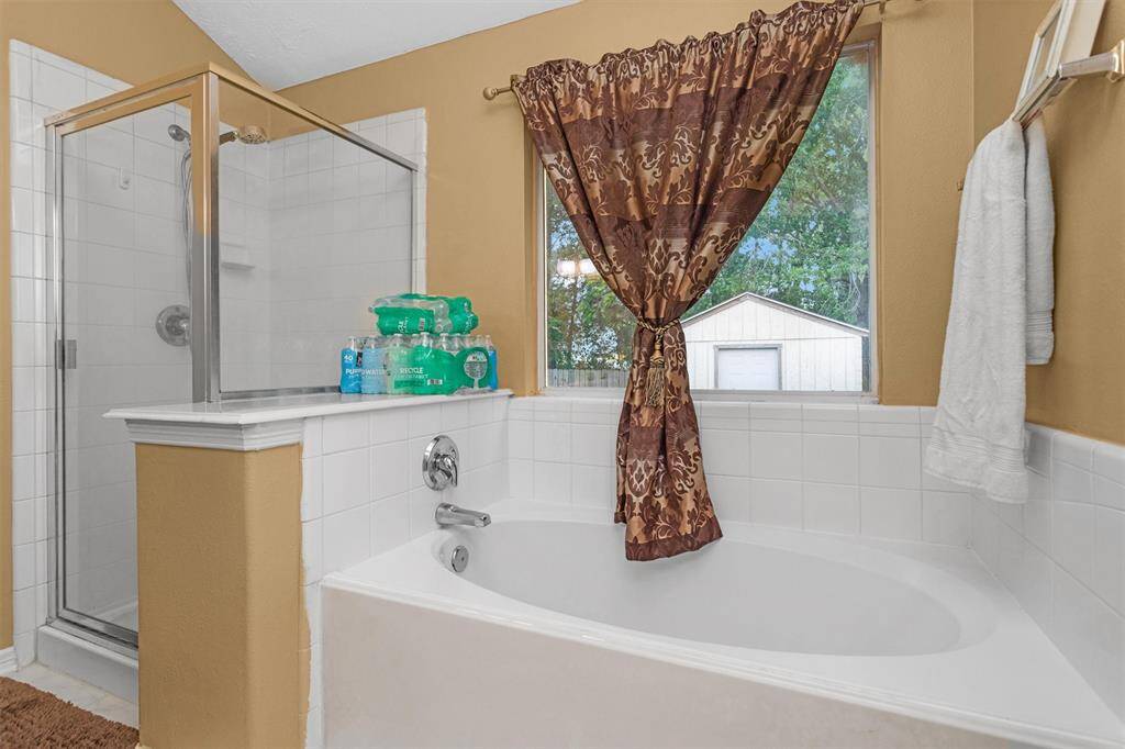 Luxurious primary bathroom featuring a spacious soaking tub, elegant shower, and abundant natural light for a relaxing retreat.