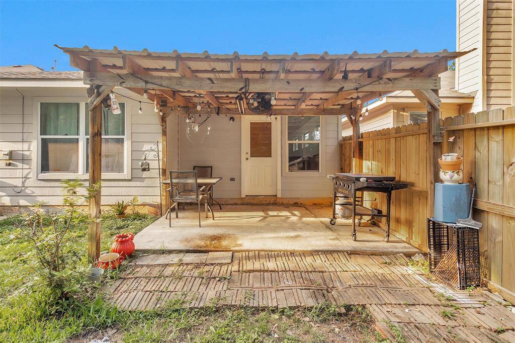 Cozy back patio with a charming pergola, perfect for outdoor dining and relaxation.