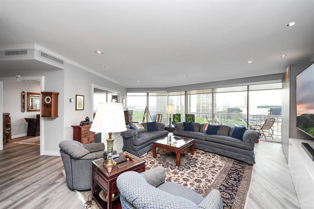 This spacious living room features large windows with city views. The open layout and abundant natural light create a welcoming ambiance.