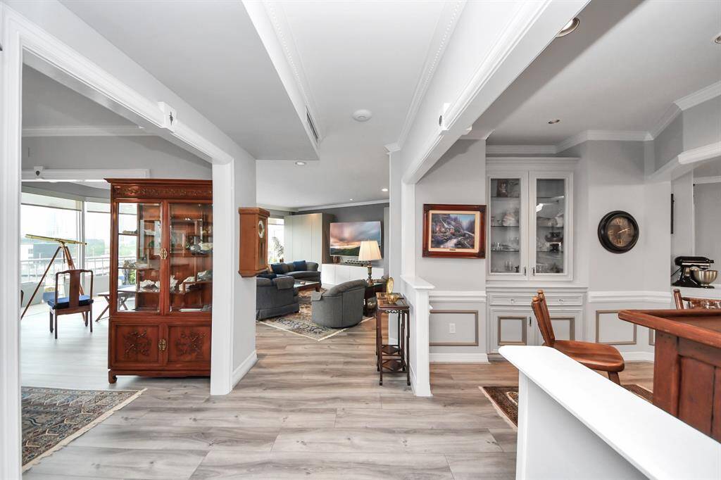 This photo showcases a modern, open-concept living and dining area with large windows offering city views. The space features elegant hardwood flooring, a stylish chandelier, and ample natural light, creating a warm and inviting atmosphere.