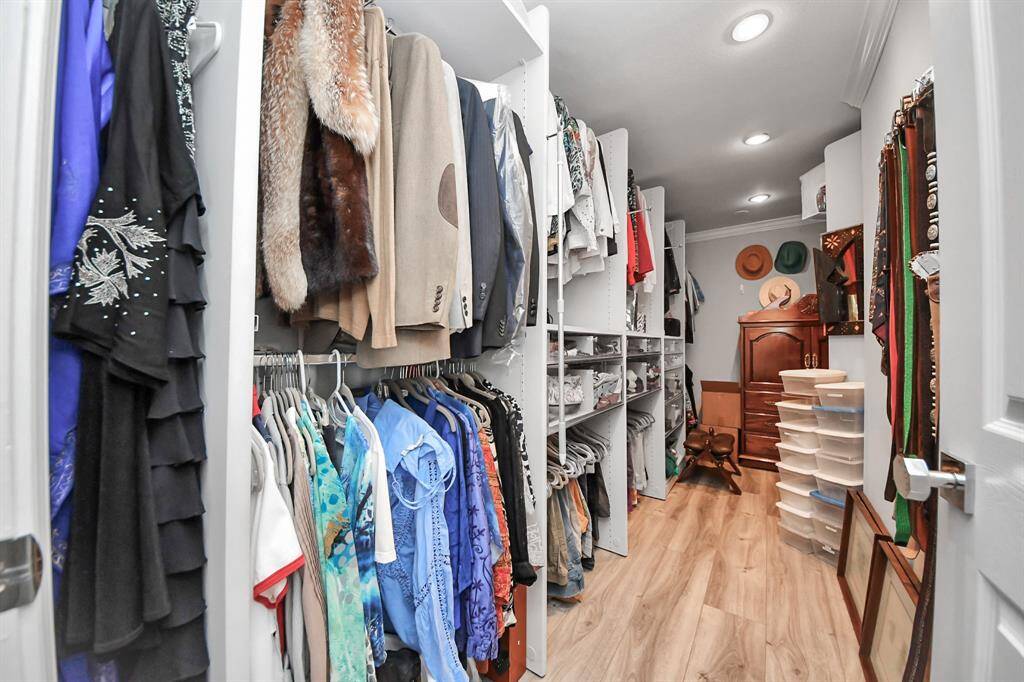 Your spacious walk-in closet with ample storage, featuring hanging rods, shelves, and built-in drawers. It has a well-lit, organized with even more room around the corner.