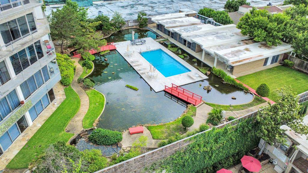This property features a central swimming pool surrounded by landscaped greenery, a serene pond, and charming red bridges. The modern architecture and ample outdoor space offer a tranquil and inviting atmosphere.