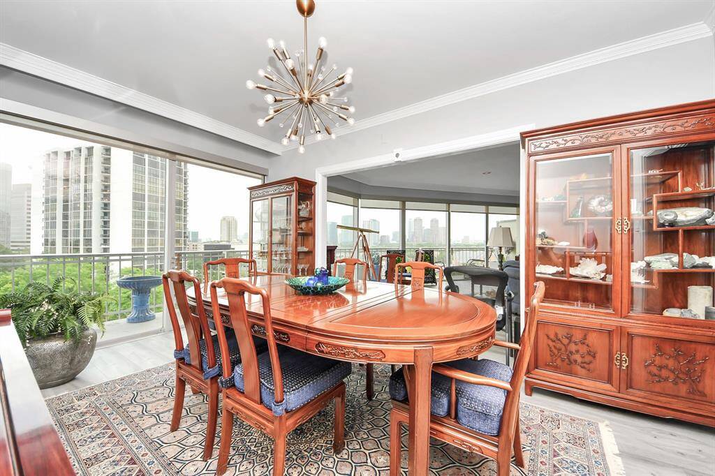 Imagine family and friends in the formal dinning room with a stylish modern chandelier. The space is well-lit with natural light from large windows offering views of the city skyline.