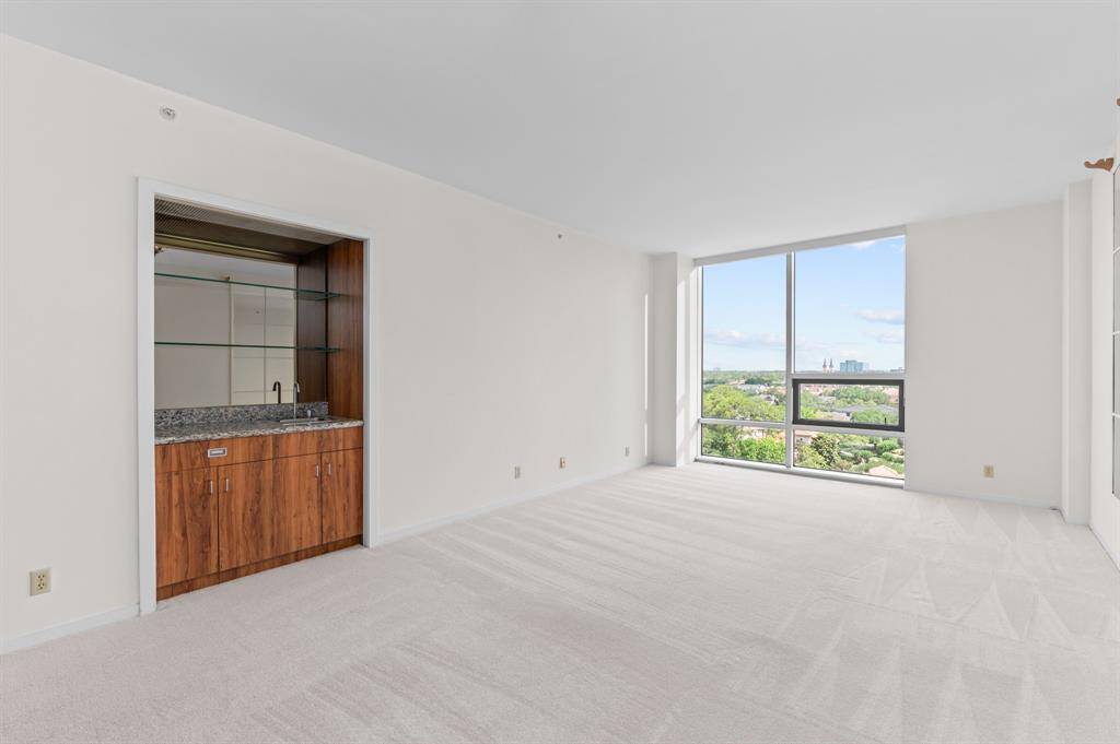 Bright and spacious room with large windows offering a scenic city view. Neutral walls and carpet create a blank canvas for personalization.