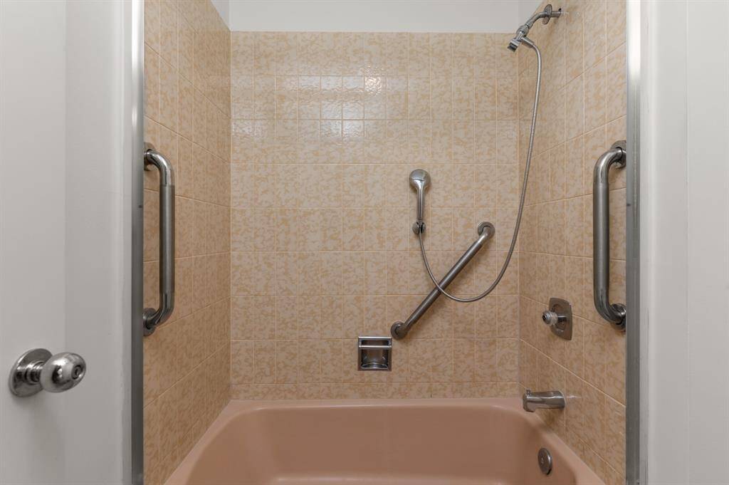 This bathroom features a vintage-style bathtub with a showerhead and grab bars, surrounded by patterned tiles. There's also a bidet, offering a unique touch.