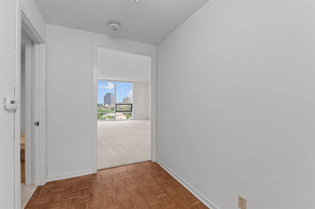 This photo shows a spacious, built-in closet with white sliding doors, featuring a single hanging rod, ideal for organizing clothes and maximizing storage space.