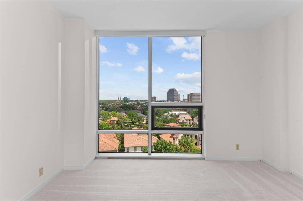 Bright, minimalistic room with large windows offering a scenic view of the city skyline and greenery. Perfect for a serene living space or an office.