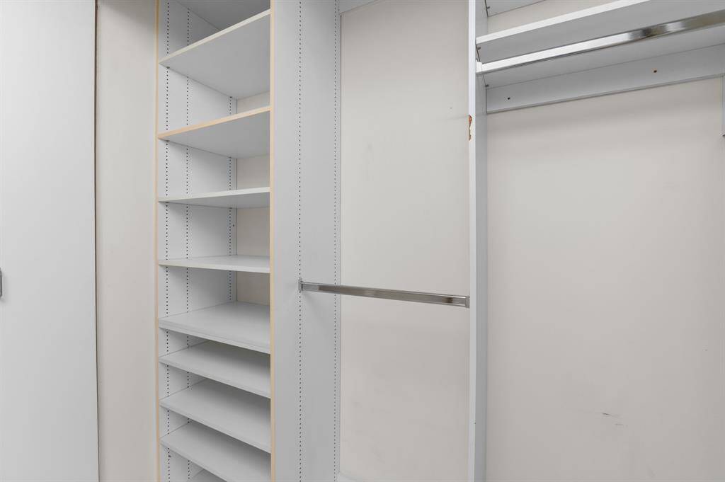 This shows a clean, spacious walk-in closet with multiple shelves and a hanging rod, ideal for organized storage.