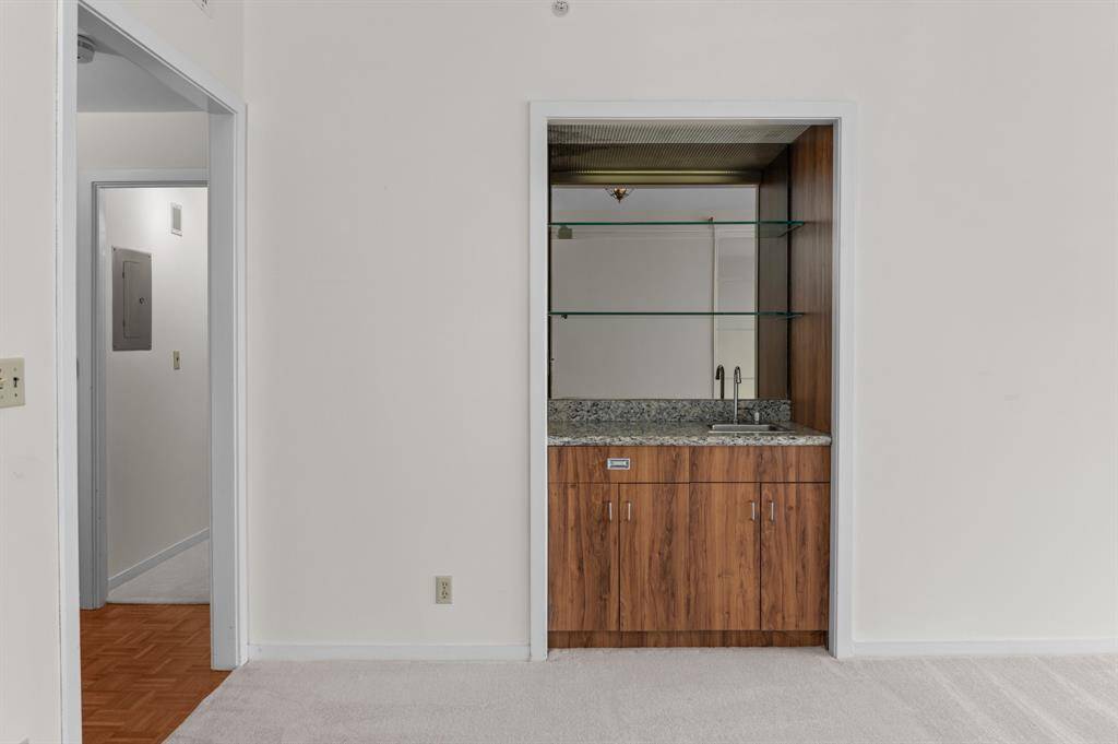 Bright and spacious room with a large window offering a cityscape view. Features a ceiling fan and neutral-toned walls and carpet, providing a versatile space for personalization.