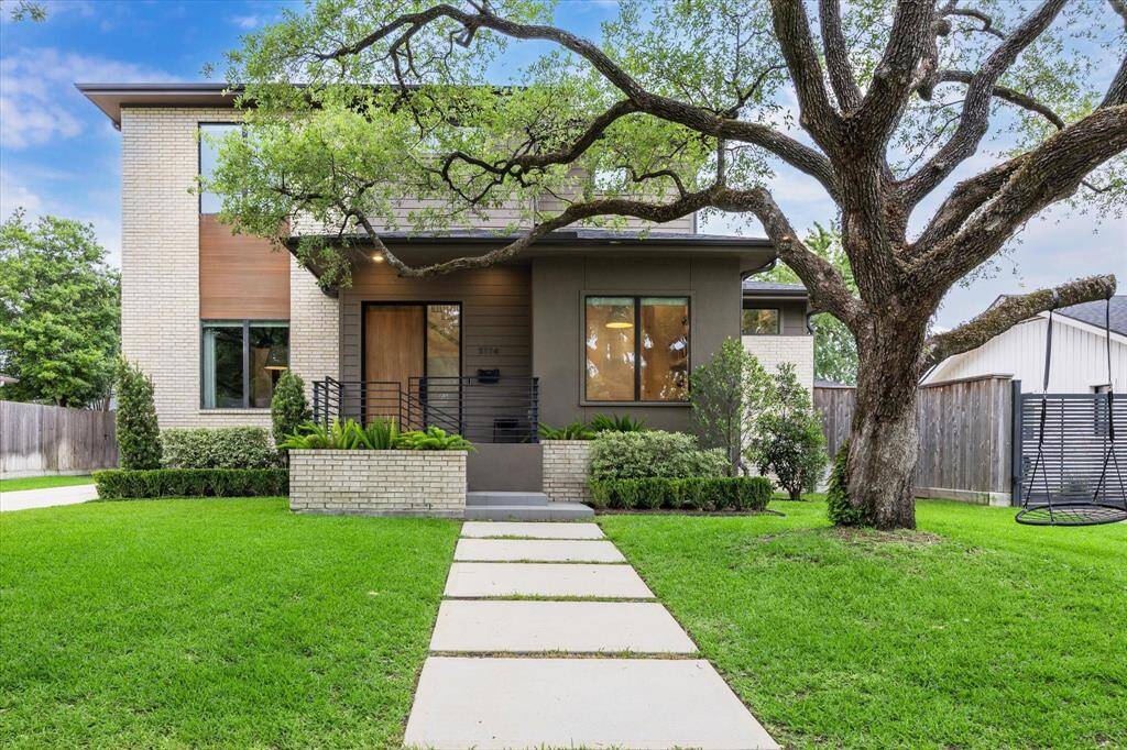 A striking fusion of contemporary design and natural elegance, this Meyerland residence showcases clean architectural lines, warm wood accents, and a graceful canopy of mature trees. The manicured lawn and inviting pathway lead to a bold entryway, setting the tone for refined living within.