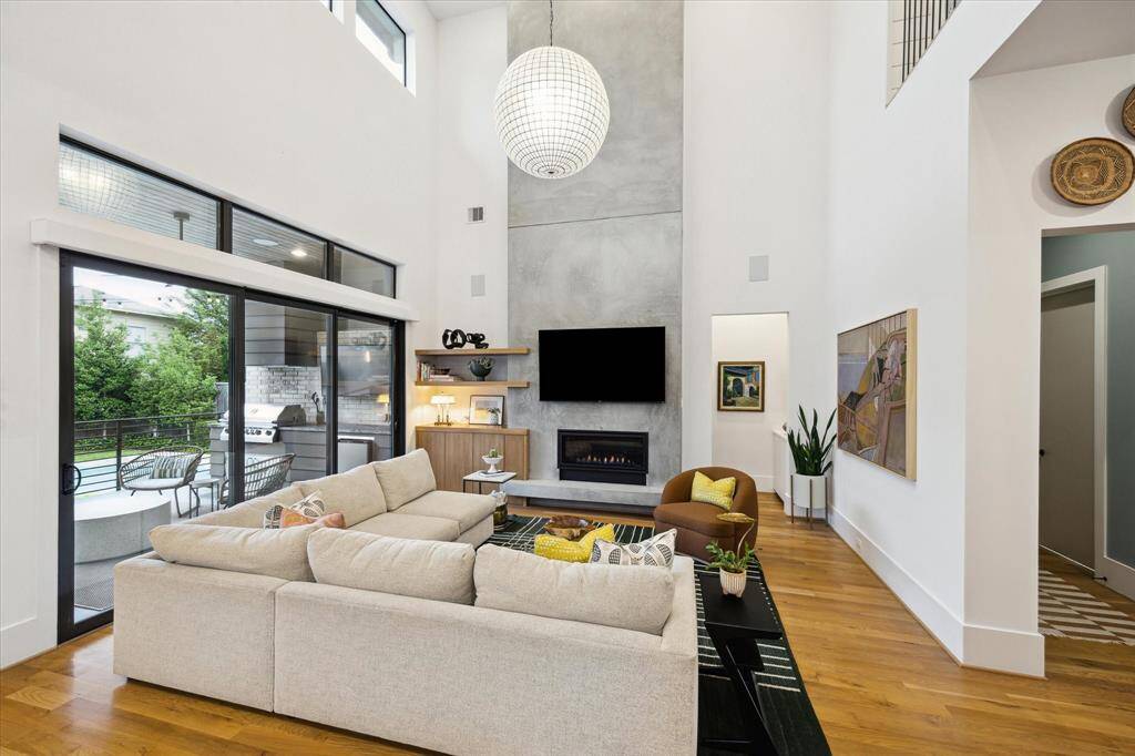 Expansive and light-filled, this soaring living room pairs a dramatic floor-to-ceiling concrete fireplace with seamless indoor-outdoor flow through oversized sliding glass doors.