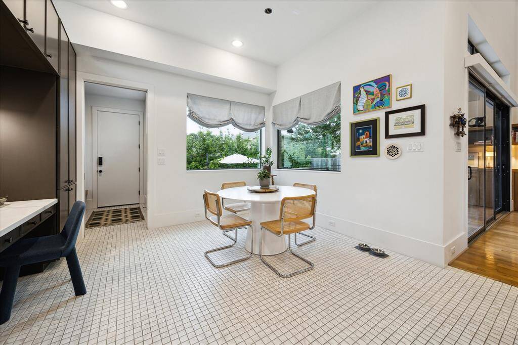 Framed by wraparound windows and vibrant art, this cheerful breakfast room offers a stylish and sunlit space for casual dining with views of the lush backyard.