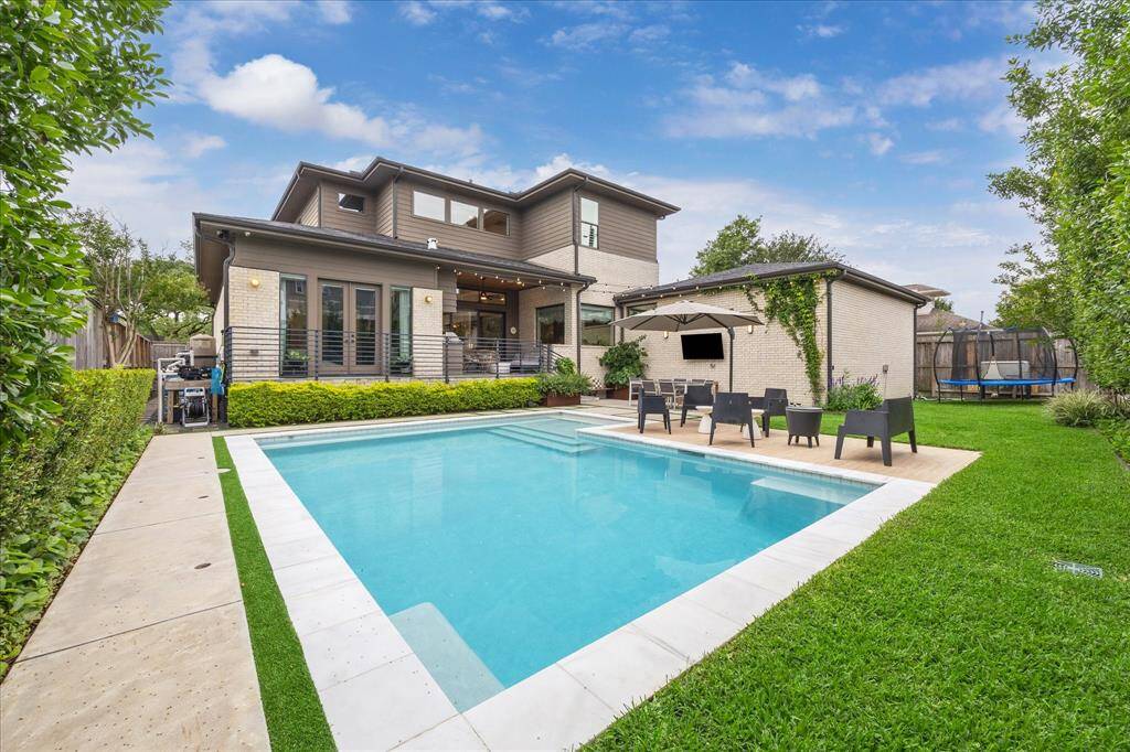 This private backyard oasis is a flawless blend of sophistication and leisure, featuring a pristine pool framed by lush greenery and sleek stonework. The covered patio and alfresco lounge area invite effortless entertaining under the open sky.
