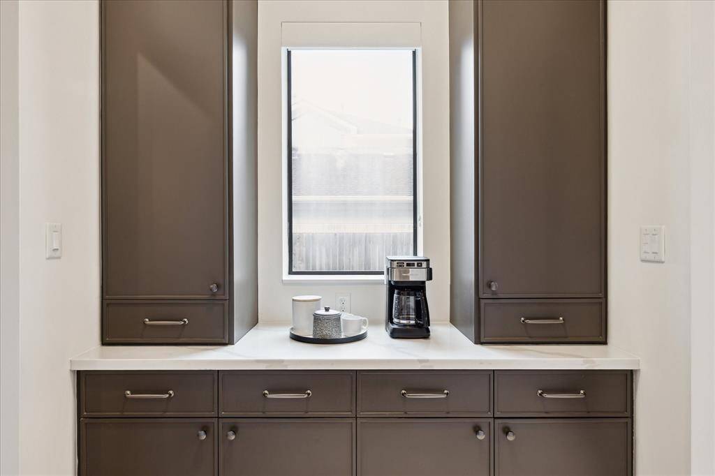 This chic built-in coffee bar pairs sleek taupe cabinetry with a crisp quartz countertop, creating a serene and stylish space to start your day.