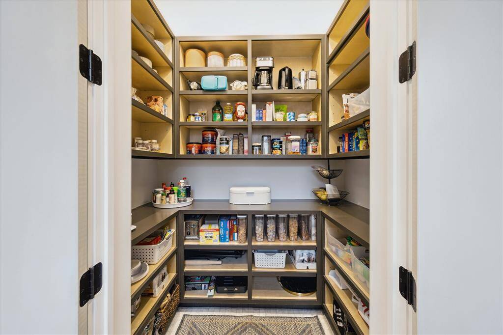 This walk-in pantry is a masterclass in organization, featuring custom open shelving, ample counter space, and thoughtful storage solutions for effortless kitchen functionality.