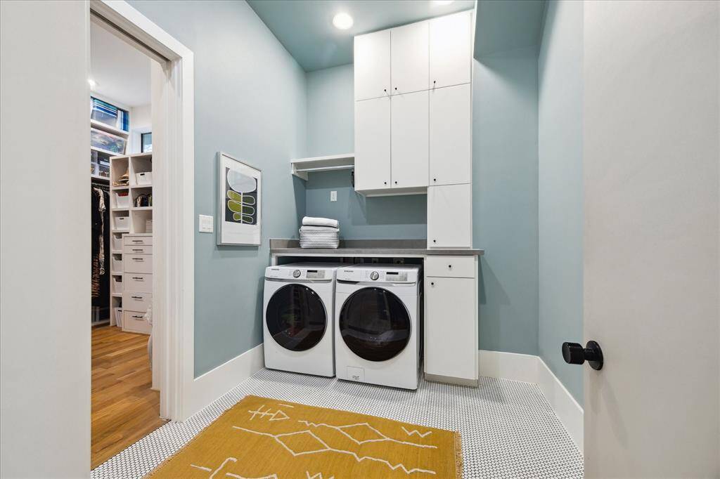 Conveniently located just off the primary closet, this stylish laundry room features custom cabinetry, ample folding space, and cheerful design touches—all wrapped in a calming palette that turns daily chores into a refined experience.