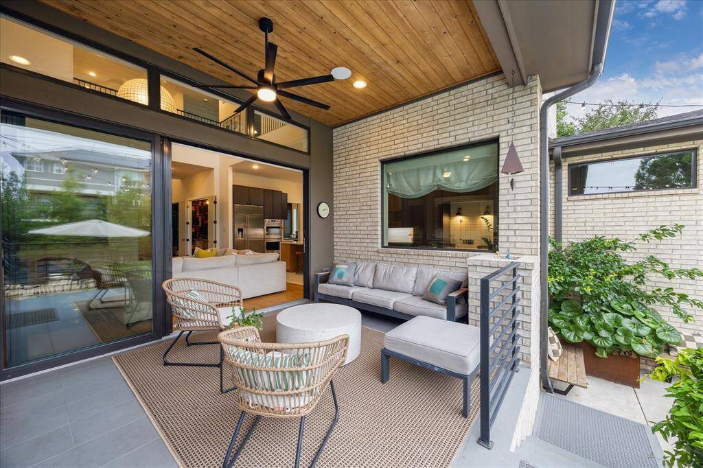 This inviting outdoor living space blends comfort and style beneath a warm wood-paneled ceiling, complete with recessed lighting and a sleek modern fan for year-round enjoyment. Seamlessly connected to the interior through expansive glass sliders, it offers the perfect setting for relaxed lounging or effortless entertaining.