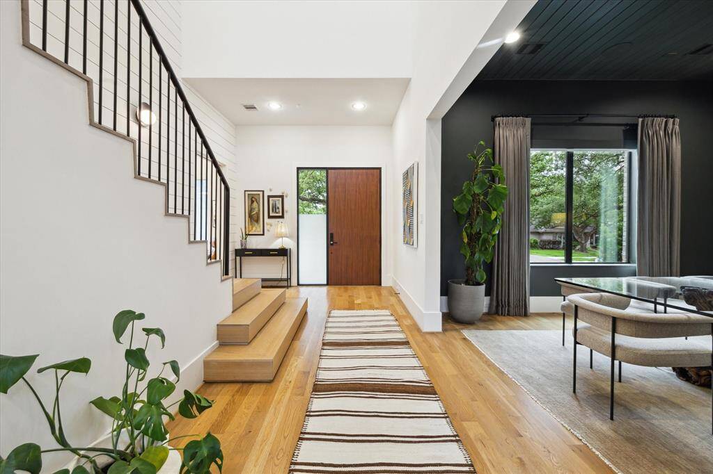 A bold wood front door with frosted glass sidelight opens to a stunning entryway defined by clean architectural lines, rich hardwoods, and thoughtfully curated design moments that set an elevated tone for the home.