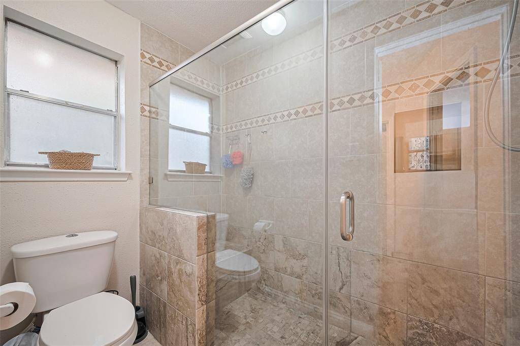 Custom extended walk in shower with bench decorative tile in primary bathroom.