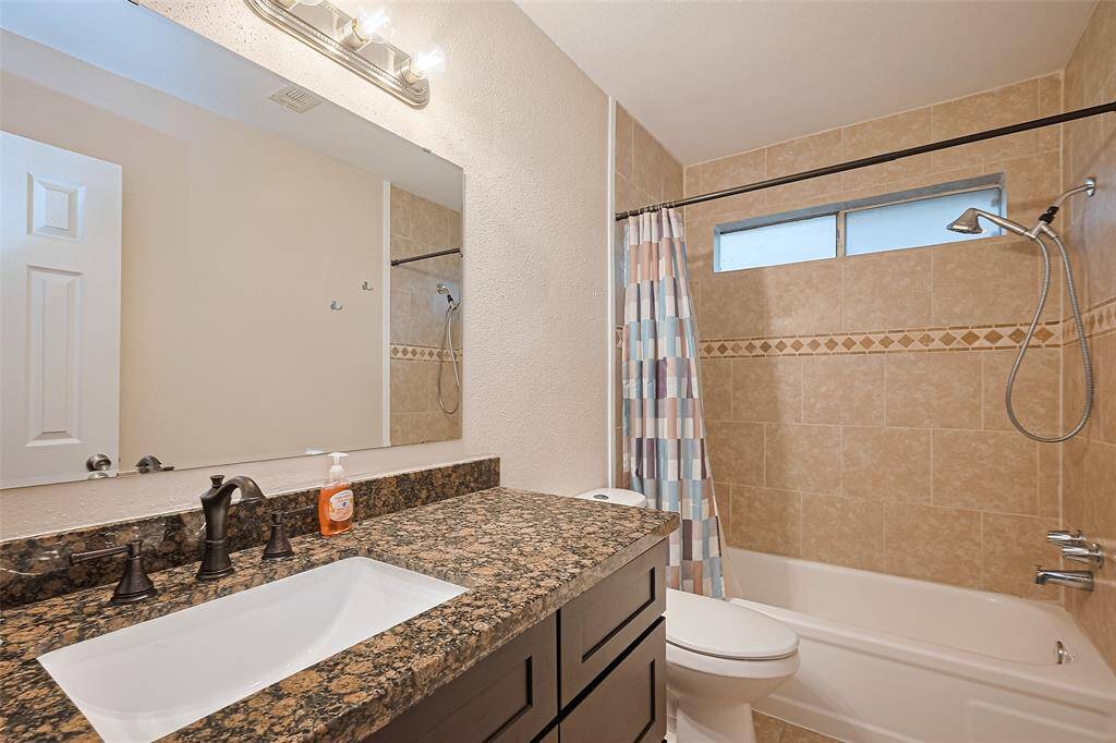 Secondary full bathroom with granite counter tops and decorative tile bath/shower combo.
