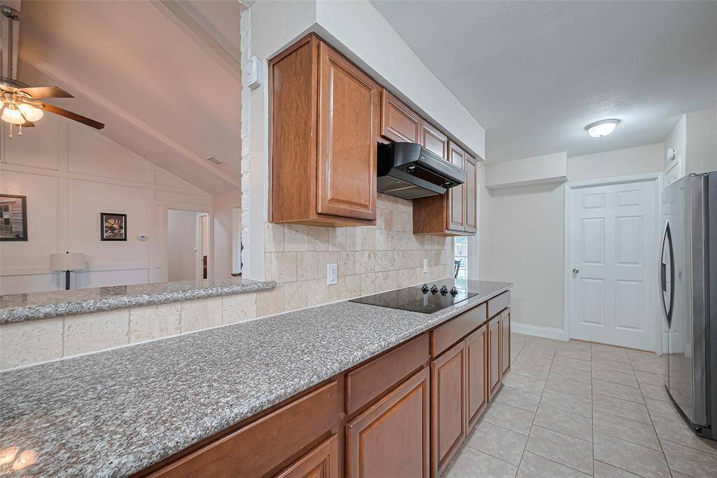 Kitchen open to living room with granite counter tops and upgraded backsplash.