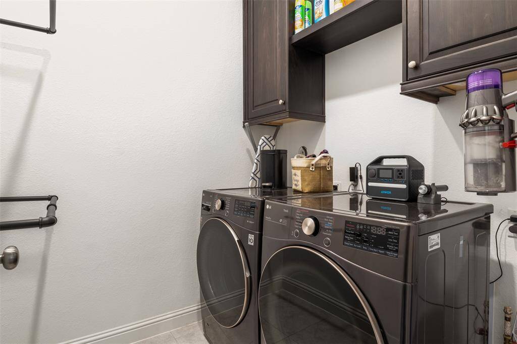 modern laundry room with dark cabinetry for storage, and a wall-mounted shelves. The space is compact yet functional, providing ample storage and utility for laundry tasks.