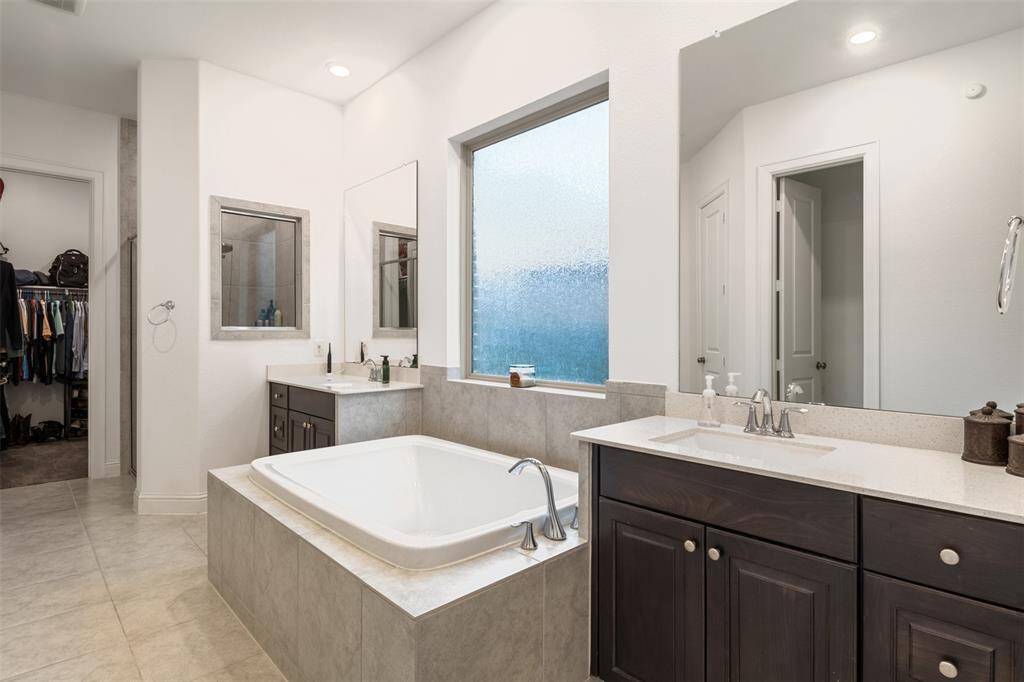 Master suite bathroom with jetted soaking tub and vanity style his and hers sinks is complimented with TWO walk in closets on each side