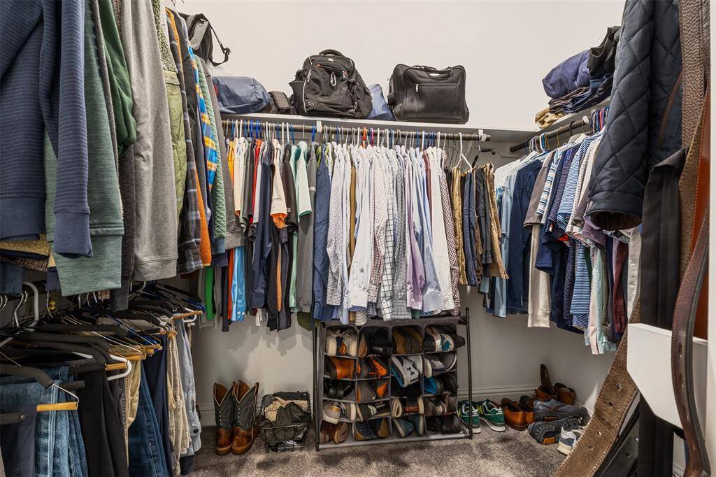 One of the TWO master suite walk-in closets with ample hanging space and built in shelves for additional storage, providing a well-organized and functional space.