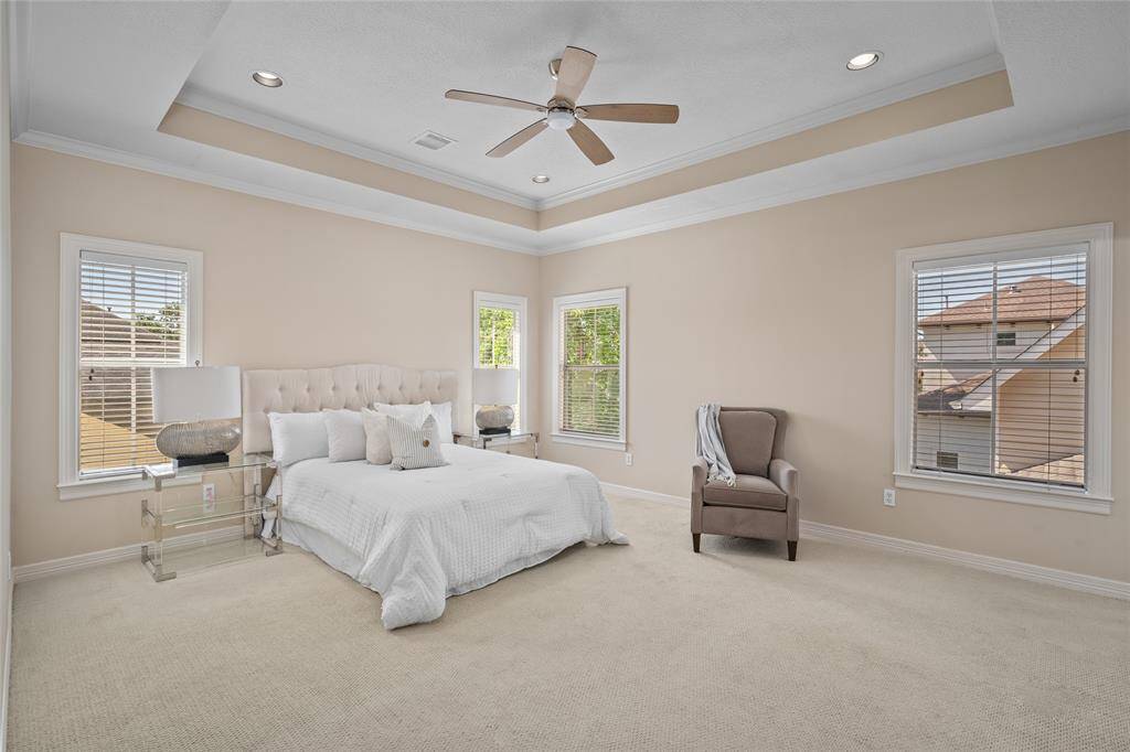 Primary bed with tray ceiling and windows overlooking the backyard.